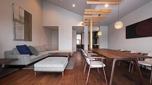 A modern living room with a sofa, a coffee table, and a dining area with a wooden table and chairs. - Orchid Furano (Furano)