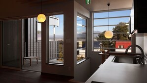 A modern kitchen with large windows, a dining area with a bench, and a view of the cityscape. - Orchid Furano (Furano)