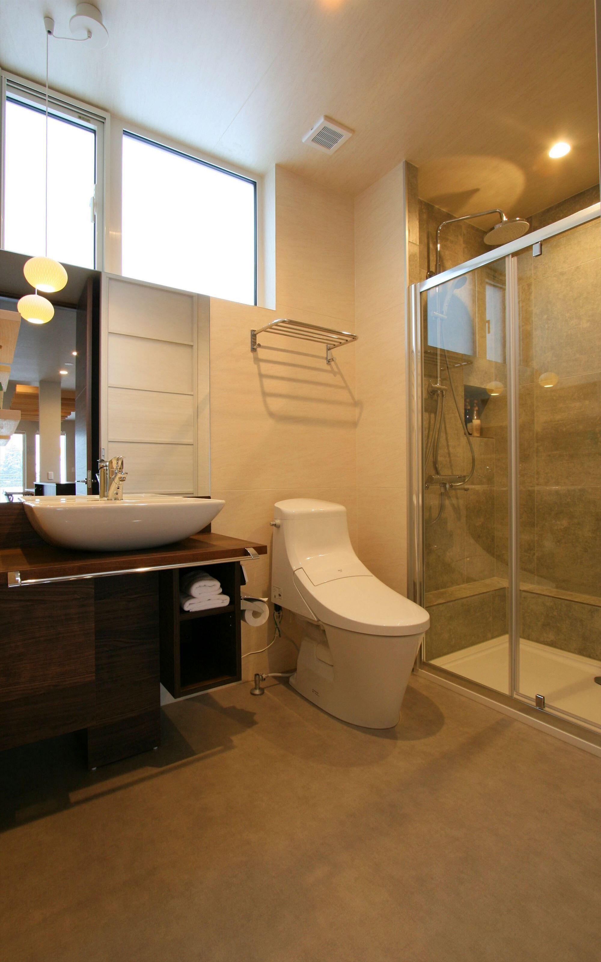 A modern bathroom with a large sink, toilet, and glass shower enclosure.