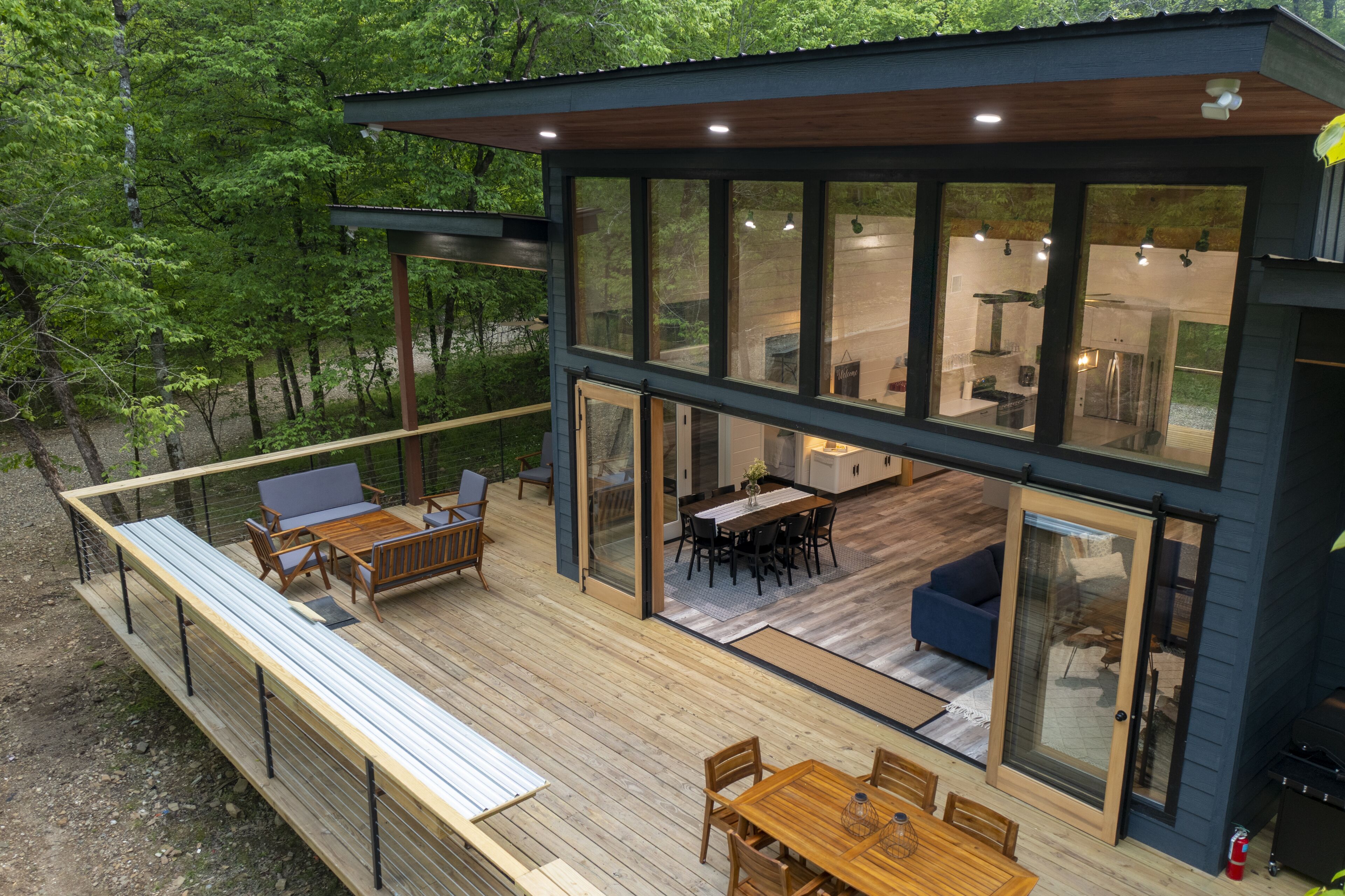 A modern house with a deck, large windows, and a dining area.