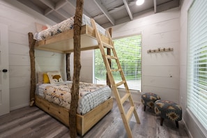 Una cama litera con escalera, una ventana con persianas y un estante pequeño con ganchos.