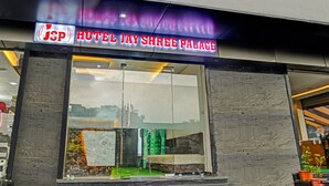 The exterior of Hotel Jay Shree Palace with a clear glass facade and a signboard displaying the hotel's name.