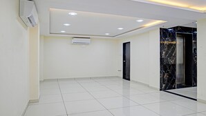 A modern hallway with white tiled flooring, recessed ceiling lighting, and a marble elevator door.