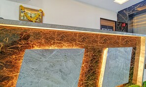 A reception desk with a marble top and a framed picture above it. - Treebo Jayshree Palace C21 Business Park (Indore)