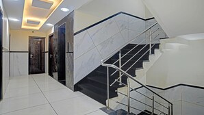 A modern staircase with a metal handrail and black steps, leading to an upper floor.