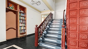 A staircase with black marble steps and a red door with floral carvings. - Itsy Hotels The Waters Edge Beach Resort (Neyyattinkara)