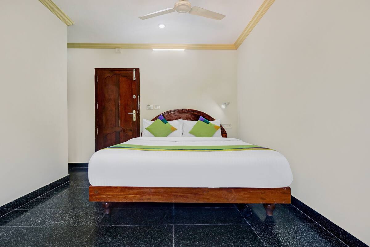 Una habitación de hotel con una cama de madera, un ventilador de techo y una puerta.
