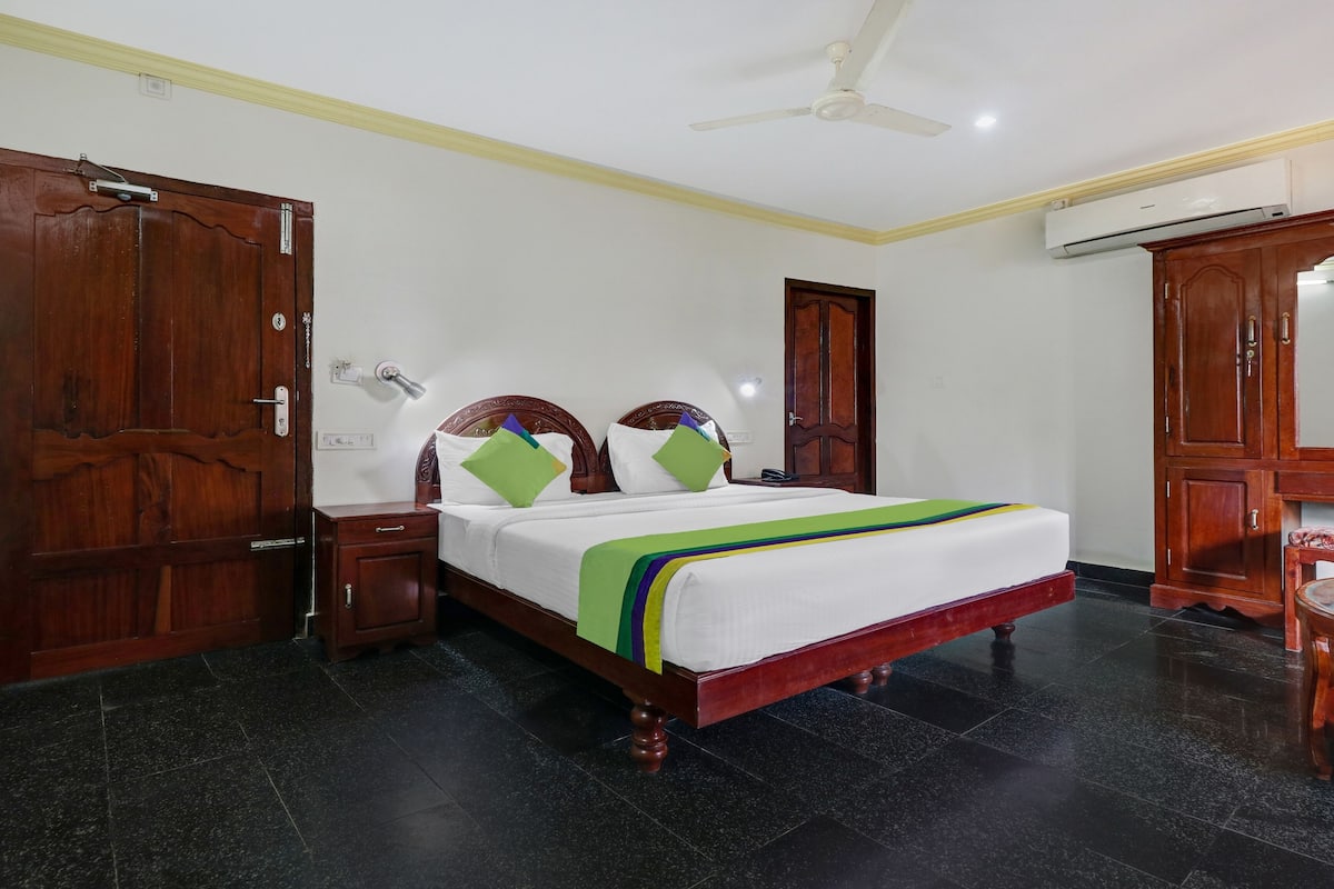 Una habitación de hotel con cama, armario de madera y ventilador de techo.