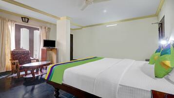 Una habitación de hotel con una cama, televisión, escritorio y una silla.