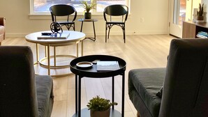 A modern living room with a large window, two chairs, a round table, and a sofa. - Paradise Valley View Getaway (Livingston)