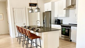 A modern kitchen with white cabinets, stainless steel appliances, and a central island with bar stools. - Paradise Valley View Getaway (Livingston)