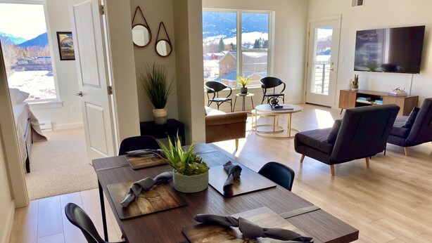 A modern living room with a wooden dining table, black chairs, a sofa, and a TV mounted on the wall. - Paradise Valley View Getaway (Livingston)