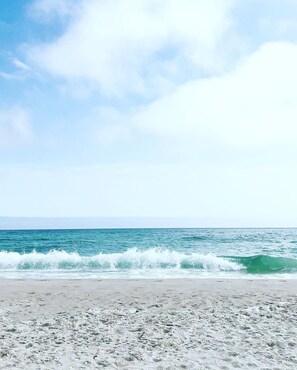 A beach with waves crashing onto the shore under a clear sky.