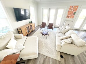 A modern living room with a large flat-screen TV, two sofas, a coffee table, and a wooden cabinet.
