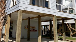 A two-story building with a balcony on the upper floor, wooden support beams, and a sign that reads "Orange Jewelers". - Excellent Location, Beautiful House Sleeps 10 and Will Feel Like Home!  (Orange Beach)