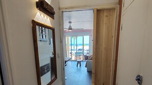 Un pasillo que conduce a vistas de la playa, con un ventilador de techo, un espejo y un banco de madera.