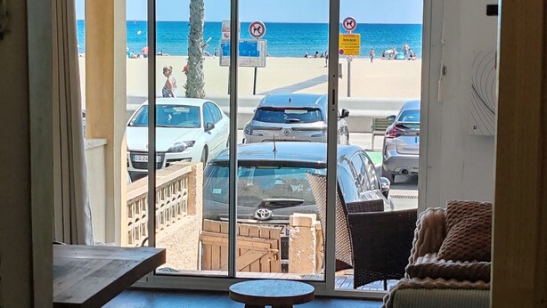 Una habitación con vista a la playa, una mesa, un sofá y piso de madera.