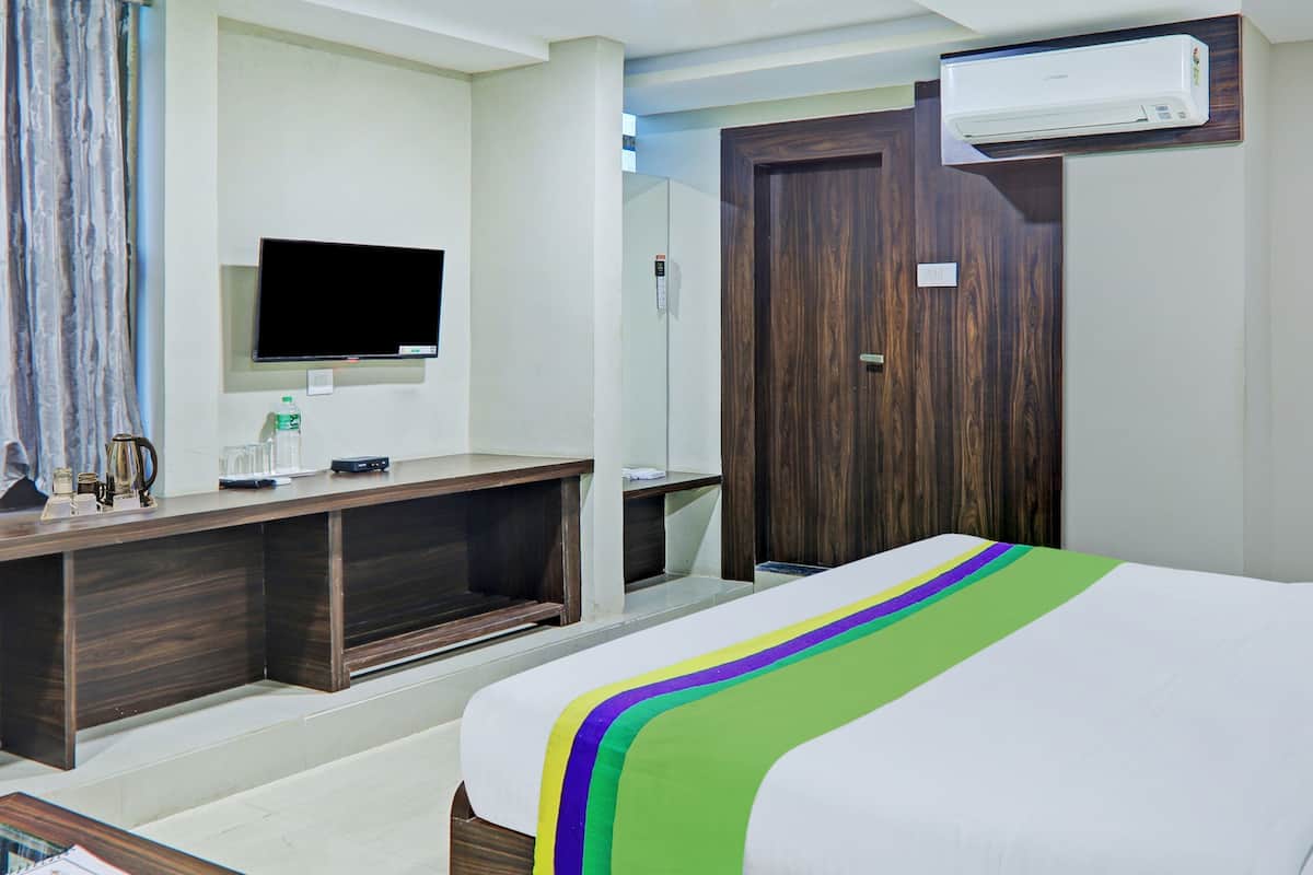 A hotel room with a bed, a TV, a desk, and a wardrobe.