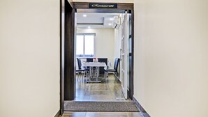 Un restaurante con entrada de madera, un comedor con mesas y sillas, y un equipo de aire acondicionado en la pared.