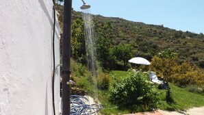 A garden with a white umbrella, a statue, and a hillside in the background. - Casa rural rodeada de arboles frutales con piscinas privadas y wifi (Cómpeta)