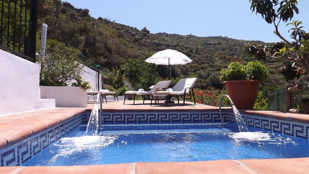 A swimming pool with a tiled edge, surrounded by lounge chairs and a white umbrella. - Casa rural rodeada de arboles frutales con piscinas privadas y wifi (Cómpeta)