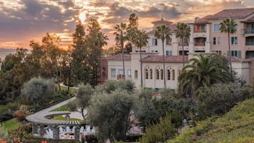 A multi-story building with a Mediterranean architectural style, featuring a central courtyard with outdoor seating and a fire pit.