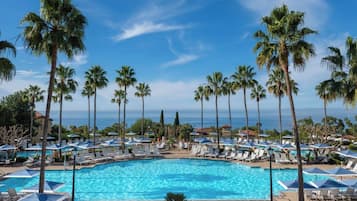 A resort pool with palm trees and lounge chairs.