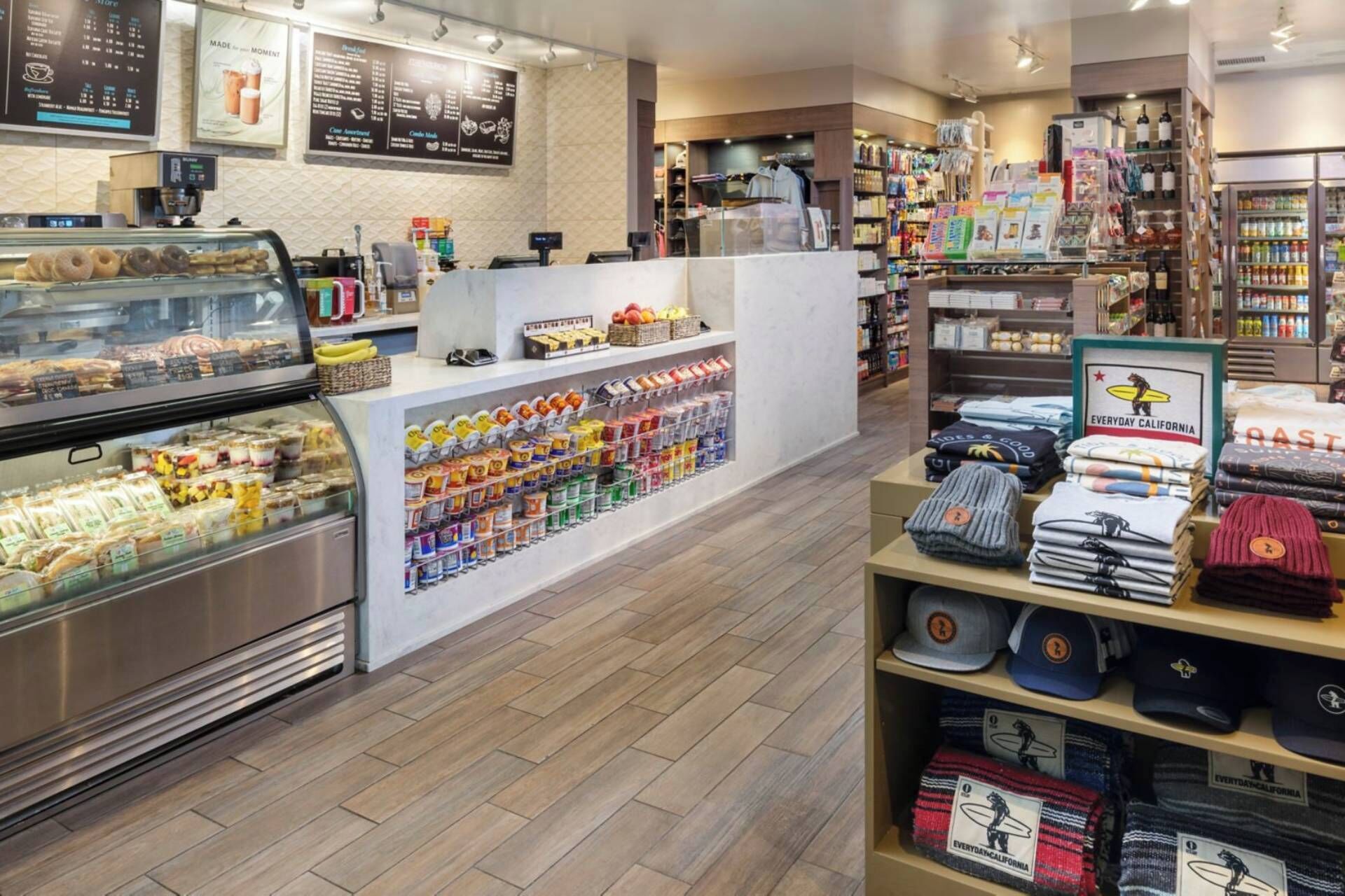 Interior de una tienda con mostrador de deli, vitrina refrigerada y estantes llenos de aperitivos y bebidas.