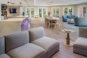 A modern hotel lobby with a bar area, seating arrangements, and large windows.
