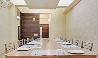 Un salón de conferencias con una larga mesa, sillas y un cartel de 'No Fumar' en la pared.