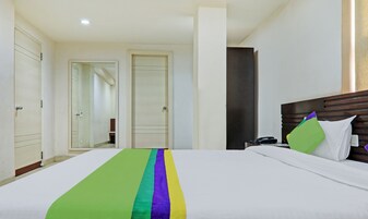 Una habitación de hotel con una cama, cabecera de madera, teléfono y espejo.
