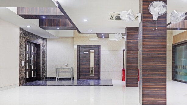Un moderno vestíbulo con suelo de mármol, puerta de madera oscura y ventiladores de techo.