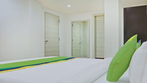 Una habitación de hotel con una cama, un almohadón verde y tres puertas.