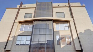 Un edificio moderno con fachada de vidrio central, múltiples ventanas y techo plano.