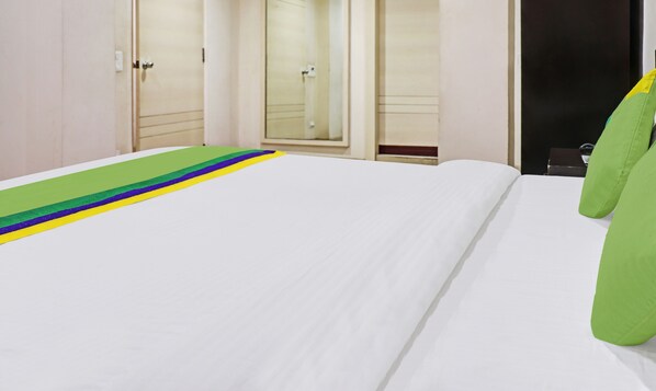 Una habitación de hotel con una cama bien hecha, una almohada verde y un corredor a rayas.