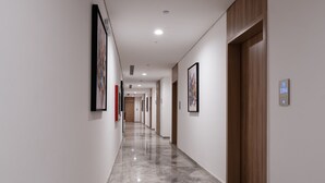 Een moderne hotelgang met een gepolijste marmeren vloer, kunstwerken aan de muren en een digitaal displaysysteem voor de lift.