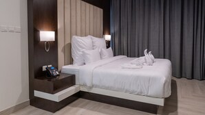 Een moderne hotelkamer met een groot bed, een bedtafeltelefoon en twee wandlampen.