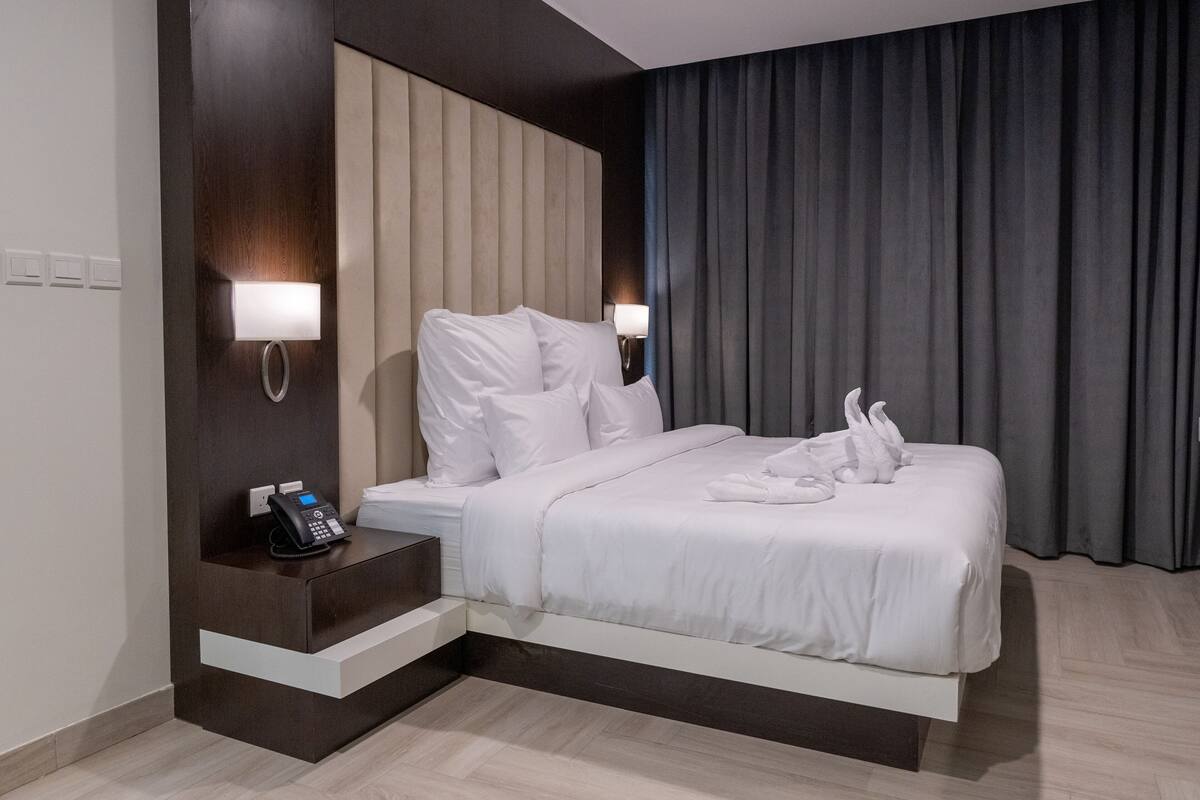 Une chambre d’hôtel moderne avec un grand lit, des lampes de chevet, un téléphone sur la table de chevet et un rideau.
