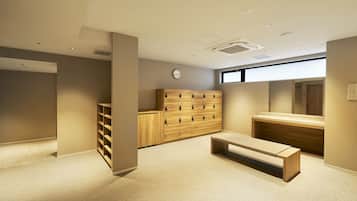 A modern, well-lit room with a wooden cabinet, a bench, and a clock on the wall.