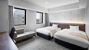 Een moderne hotelkamer met twee bedden, een bureau en uitzicht op de stad.