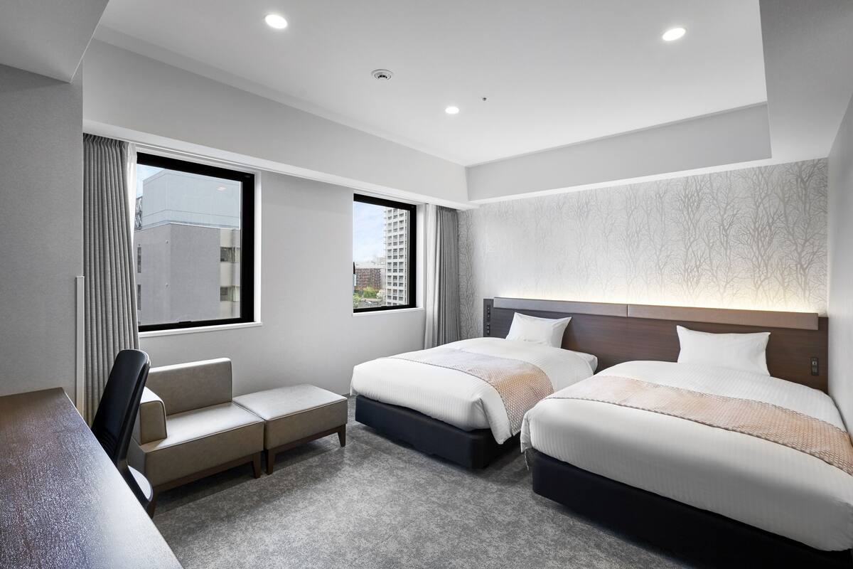 Une chambre d’hôtel moderne avec deux lits, un bureau et une vue sur la ville.