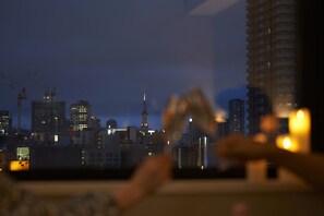 A cityscape at dusk with illuminated buildings and construction cranes.
