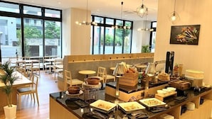 Een modern café met een centrale balie waar eten en drinken gepresenteerd worden, houten meubels en grote ramen met uitzicht op het omliggende landschap.