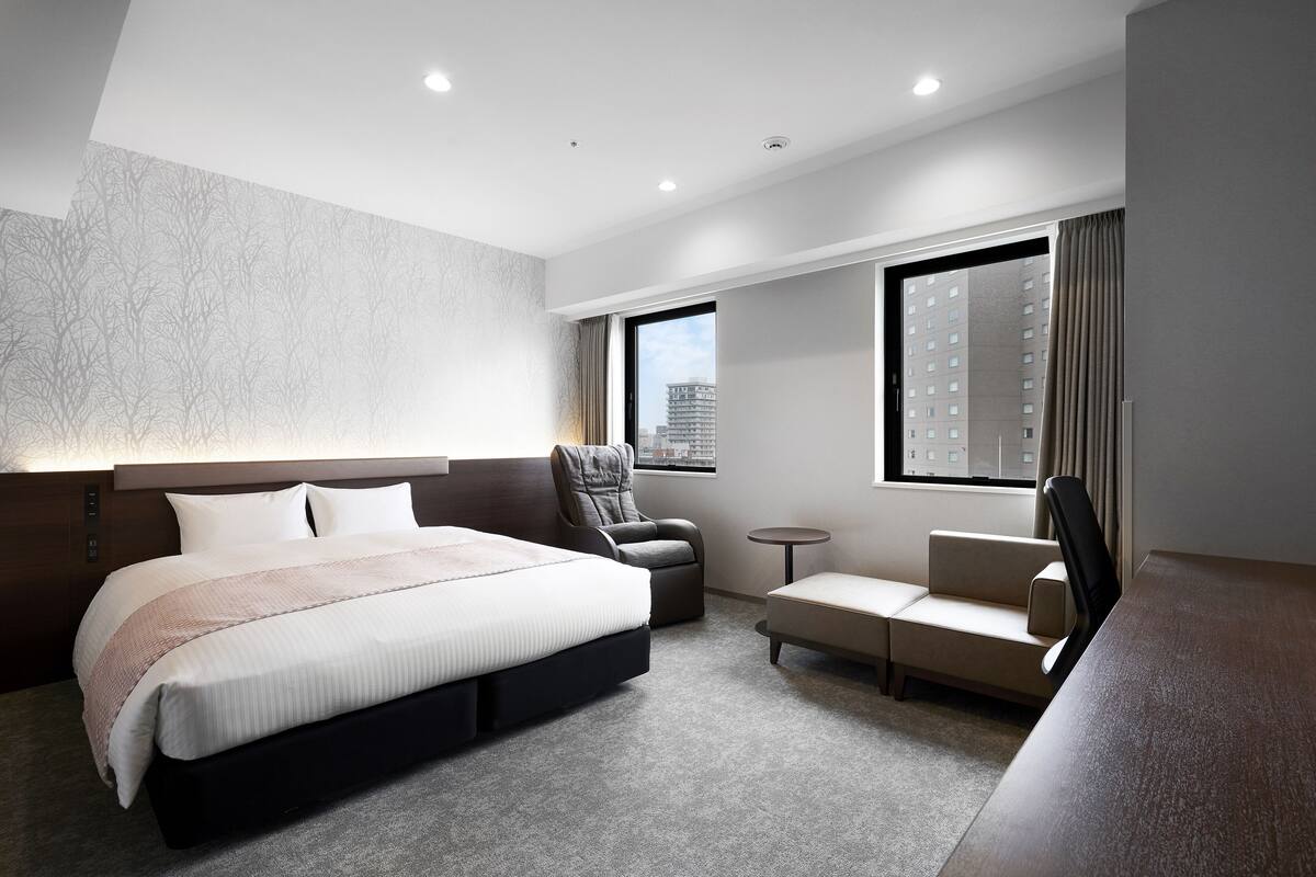 Une chambre d’hôtel moderne dotée d’un grand lit, d’un coin salon et offrant une vue sur la ville.