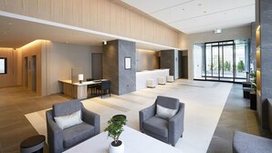 Een moderne lobby met een receptiebalie, een zithoek en grote ramen.