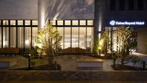 Het exterieur van Hotel Daiwa Roynet, met een modern ontwerp, met grote ramen en een goed verlicht terras.