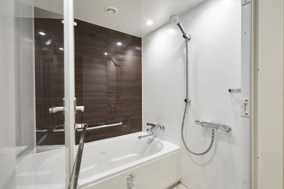 Une salle de bain moderne avec une baignoire blanche, une cabine de douche en verre et un mur recouvert de panneaux en bois.