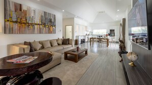 A spacious living room with a large sofa, a coffee table, and a dining area with chairs and a table.