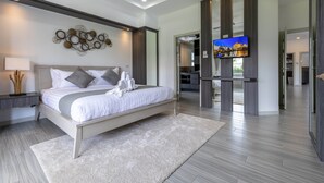 A modern bedroom with a large bed, a TV, and a walk-in closet.