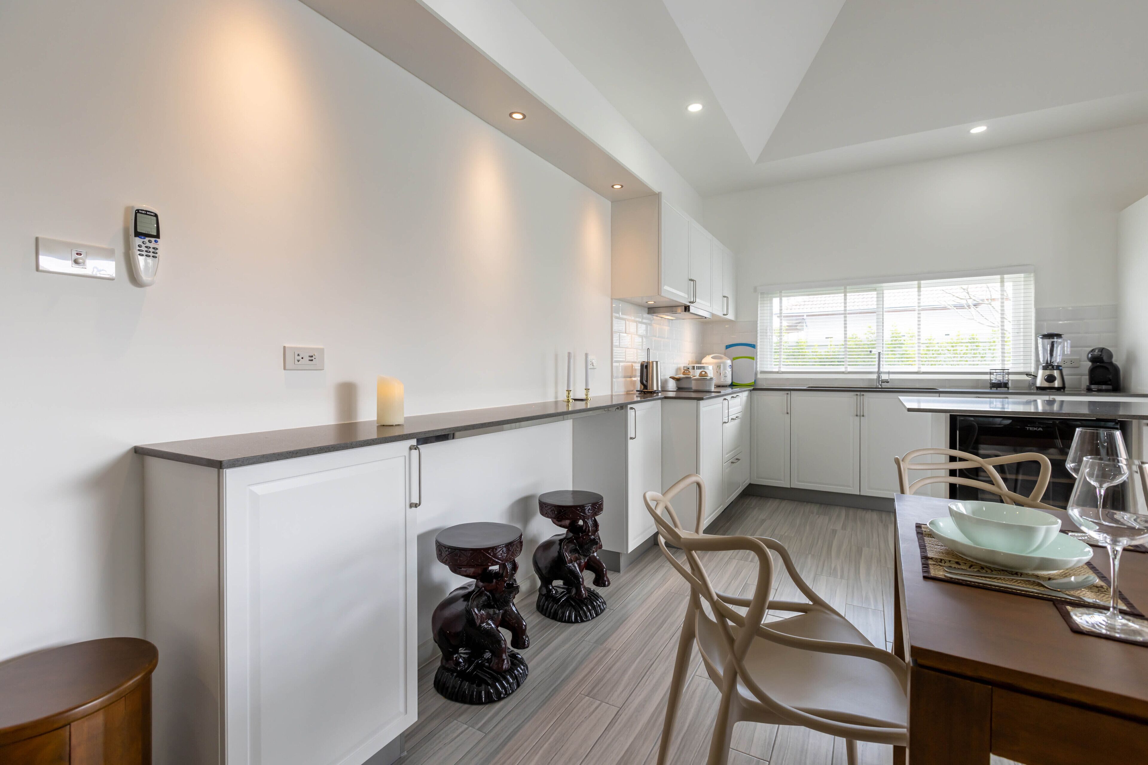 Een moderne keuken met witte kasten, een inbouwoven en een raam voor natuurlijk licht.